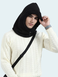 Person wearing a black hooded garment over a white sweater against a light gray background