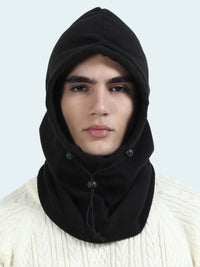 Person wearing a black hooded balaclava over a white sweater on a light gray background