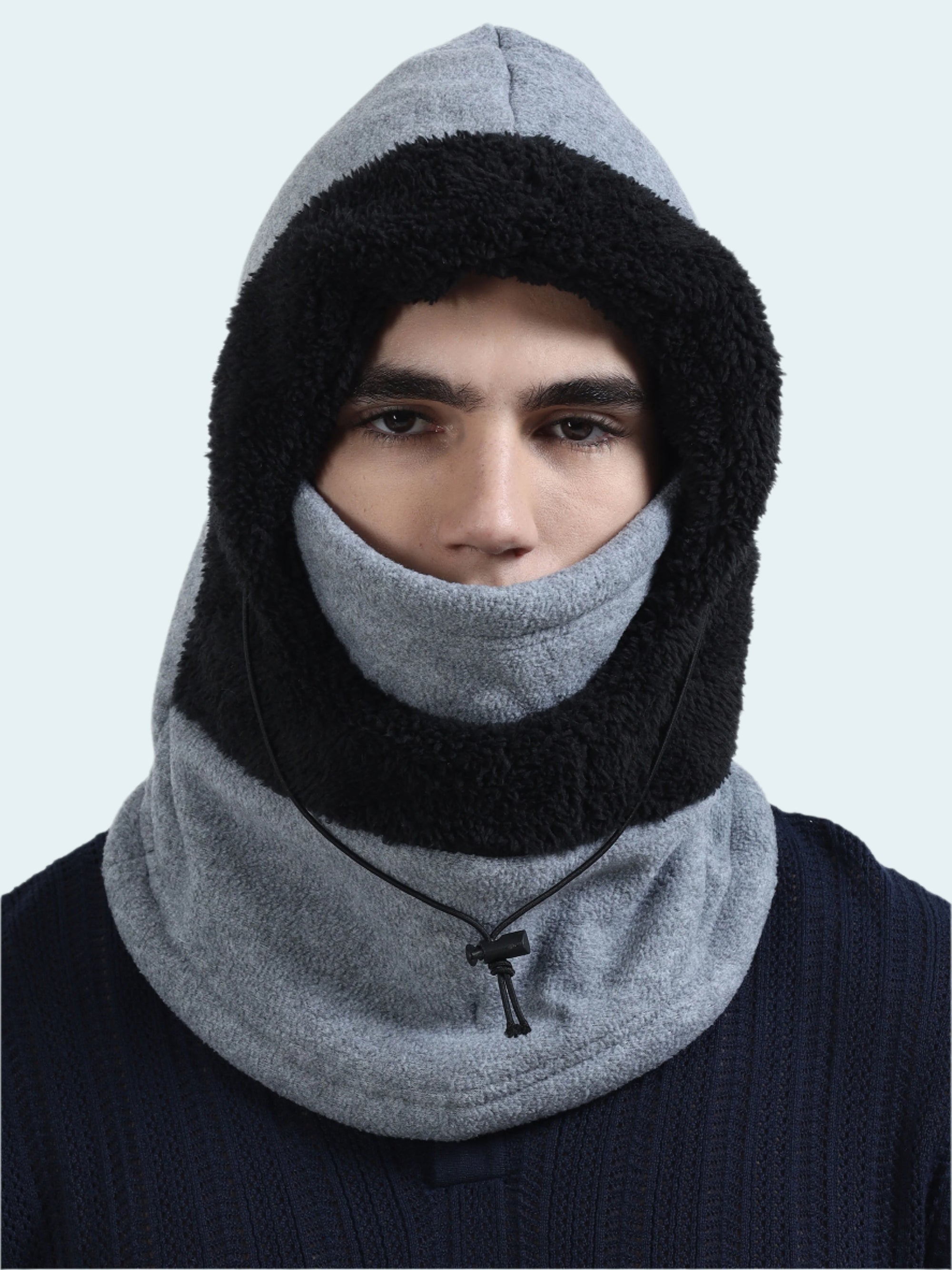 Person wearing a gray and black balaclava on a light gray background