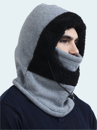 Person wearing a gray and black hooded balaclava on a light gray background